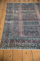 Distressed Turkmen rug's aubergine and charcoal geometric motifs, showing textured, faded pile.