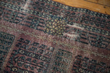 Distressed Turkmen rug texture detail, aubergine field, charcoal patterns, visible foundation wear.