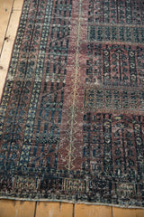 Textured fringe and time-softened aubergine and charcoal design on the distressed Turkmen rug.