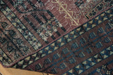 Distressed Turkmen rug with worn aubergine pile and geometric blue border.