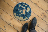 Tattered edge and worn indigo, beige texture of the antique Peking round rug.