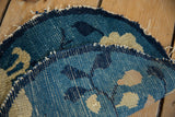 Detail of antique Peking rug's hand-knotted foundation, worn blue-beige pile, and tattered edge.