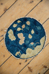 Angled close-up of antique Peking rug's curvilinear blue and beige foliage with tattered edge.