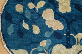 Antique Peking pictorial rug showing cobalt and beige leaf design with tattered edge.
