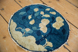 Tattered side of antique Peking round rug with cobalt blue and ivory leaf pattern.