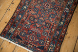 Vintage Hamadan rug close-up: traditional Herati motifs in brick red, navy, and blush with mostly even wear.