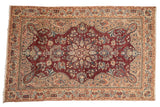 Decorative vintage distressed Sarouk rug, wine red floral medallion, ivory border, sapphire blue accents. Size 5' x 7'9
