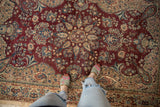 Curvilinear floral medallion on a distressed vintage rug in wine red, ivory, sapphire.