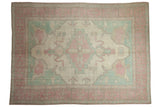 Vintage distressed Oushak carpet with serrated medallion in soft ivory, pink, and powder blue.