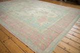 Distressed Oushak carpet corner with dusty blue and pink border, revealing subtle field motifs.