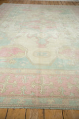 Textured pink, ivory, and powder blue patterns on the lower border of the vintage Oushak rug.