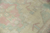 Distressed Oushak carpet pile texture with faded ivory, pink, and dusty blue patterns.