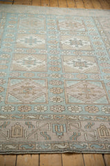 Distressed Oushak rug's geometric paneled medallions and faded blue, beige floral motifs.