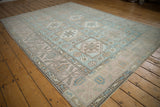Distressed vintage Oushak carpet corner with pale dusty blue and beige geometric patterns.