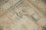 Distressed Sivas carpet detail: muted beige, blush, and navy floral gul motifs with vine borders.