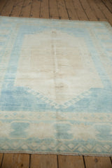 Distressed texture of the vintage Oushak rug's pale blue geometric border and intact selvage.