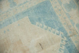 Vintage Oushak rug's distressed low pile with pale blue and ivory stepped pattern.
