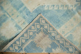 Distressed Oushak rug with soft ivory and pale blue short pile, revealing hand-knotted foundation and selvage.