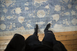 Distressed vintage Sparta carpet featuring faded sky blue field, beige floral motifs, and geometric border.