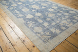 Distressed Sparta carpet detail: sky blue field, ivory vases, butterflies, and visible knot heads.