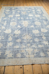 Distressed pile showing sky blue and ivory floral motifs with foundation visible.