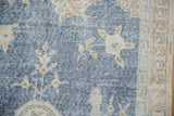 Distressed sky blue field of a Sparta carpet, with worn beige motifs and geometric border.