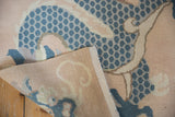 Distressed vintage Tibetan rug displaying blue dragon scales, pale peach pile, and woven foundation.