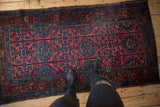 Vintage Lilihan rug with rows of floral medallions in raspberry and sapphire, showing edge tatter.