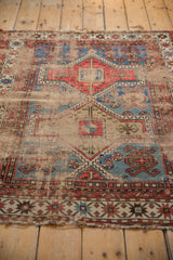 Textured surface of antique Caucasian rug, revealing foundation with geometric motifs in terracotta and blue.