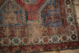 Close-up of antique Caucasian rug with threadbare field, scattered holes, tattered edge.