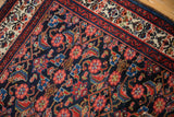 Herati motifs in ruby red on the Malayer rug's indigo field, contrasting a cream floral border.
