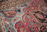 Detail of vintage Persian Doroksh carpet with vibrant ruby red, sapphire vinery, and time-softened pile.