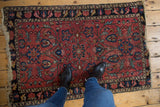 Vintage Persian Lilihan rug corner, raspberry red field, blue floral motifs, frayed fringe.