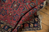 Vintage Lilihan rug's raspberry red field with sapphire floral motifs and tattered edge.