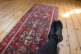 Vintage Karaja runner with geometric patterns in red and blue, displaying authentic edge wear.
