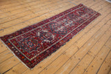 Vintage Karaja runner with geometric medallion, cherry red and navy blue, worn pile areas revealing foundation.