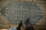 Vintage Malayer rug showing distressed pile, Herati motif, and muted blue tones.