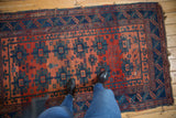 Geometric antique Caucasian rug displaying repeating indigo gul motifs on a brick red field.