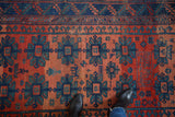 Antique Caucasian rug's brick red field displaying repeating indigo gul and figural motifs.