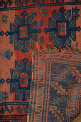 Antique Caucasian rug: geometric gul motifs, visible knot heads, woven foundation, and frayed edge.