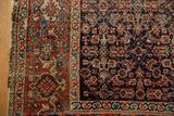 Antique Fereghan rug's navy Herati motif field meets brick red border with knot head wear.