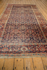 Detail of antique Fereghan carpet: brick red border and navy Herati motifs with mostly even wear.