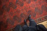 Antique Ersari carpet's chestnut red field with repeating navy blue floral gul motifs.