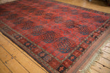 Chestnut red field of an antique Ersari carpet, featuring navy gul motifs and geometric border.