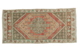 Distressed Vintage Oushak runner featuring a serrated medallion in faded terracotta and sage, 1'11