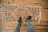 Distressed Oushak runner's serrated center medallion, germinating plant motifs, and soft terracotta, muted green hues.
