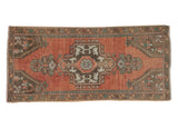 Faded distressed Oushak runner with a dusty rose ground and intricate geometric floral medallion.