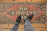 Distressed vintage Oushak runner rug with faded dusty rose ground and muted geometric floral motifs.
