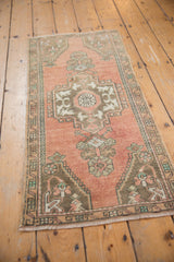 Central medallion design and geometric motifs on distressed Oushak rug's abrashed dusty rose pile.