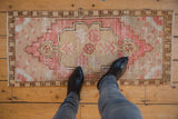 Distressed vintage Oushak rug runner, pink, ivory, beige floral medallion, displaying even wear.